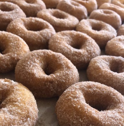 img-0201 Close-up of freshly made doughnuts coated in sugar, arranged neatly in rows, showcasing their round shape and soft texture. Perfect for a sweet treat or dessert.